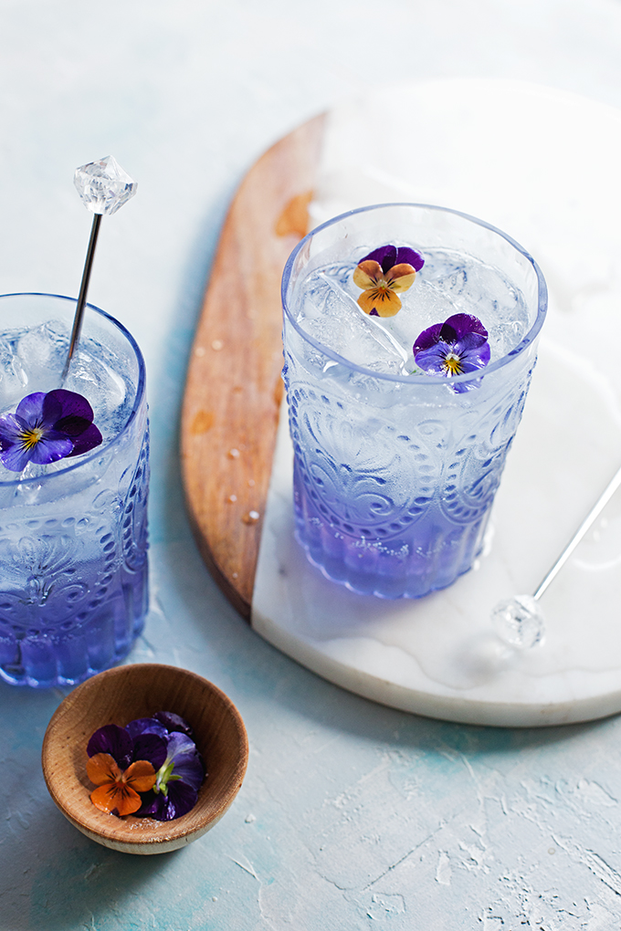 Purple iced beverage with edible flower garnish