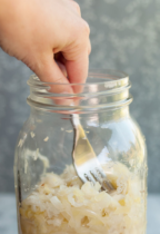 packing down sauerkraut in a jar